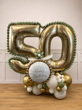 Load image into Gallery viewer, Gold and green balloon arrangement with number '50' and 'Happy Birthday' message on a wooden floor.