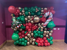 Load image into Gallery viewer, Decorative balloon arch with Christmas theme in a room with purple walls.
