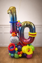 Load image into Gallery viewer, Colourful balloon arrangement with number '10' and small ball labeled 'Happy Birthday' on a wooden floor.
