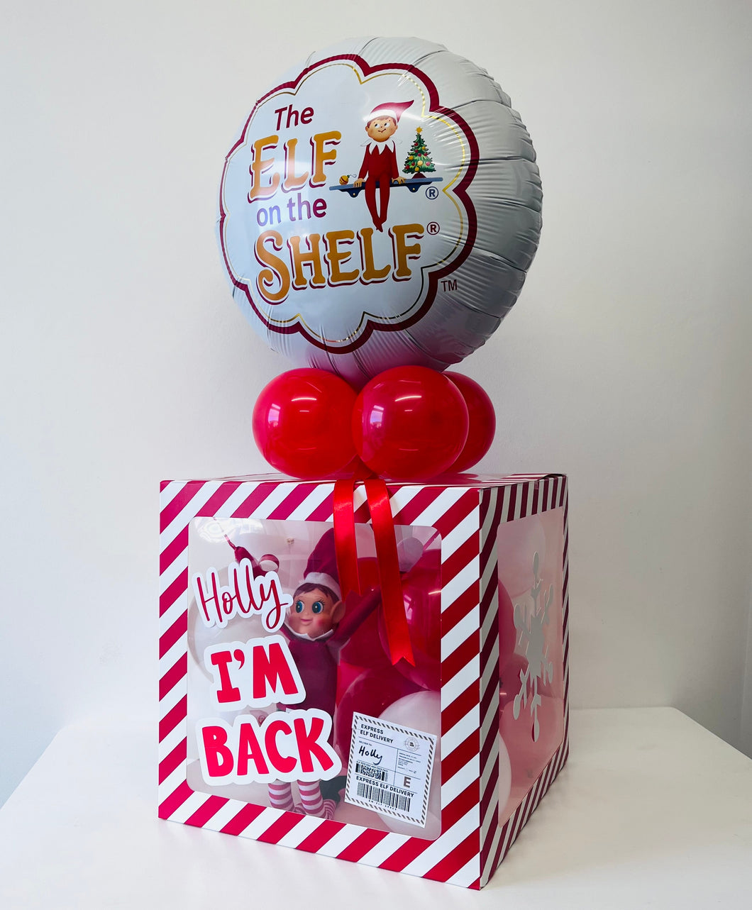 Decorative box with 'Elf on the Shelf' theme featuring balloons and a printed image of an elf.
