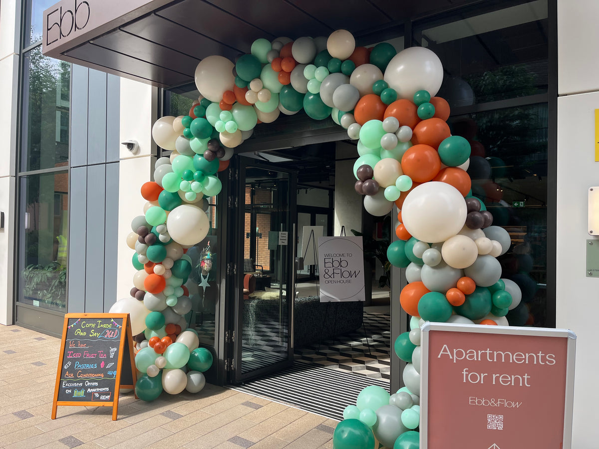 Decorative balloon arch outside an apartment building with 'Ebb & Flow' branding.