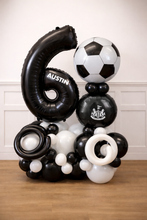 Load image into Gallery viewer, Balloon sculpture with number 6, soccer ball, and other shapes on a wooden floor.
