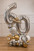 Load image into Gallery viewer, A large metallic silver and gold balloon decoration shaped like the numbers 60, with a cluster of coordinating silver, gold, white, and gray balloons at the base. A white round balloon near the center reads 'happy 60th ANNIVERSARY' in gold script.
