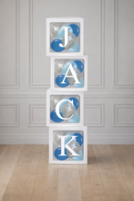 Load image into Gallery viewer, Stack of blocks with letters spelling 'JACK' on a wooden floor against a gray paneled wall.
