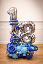 Load image into Gallery viewer, Decorative balloon arrangement with number '18' and blue and silver balloons on a wooden floor.
