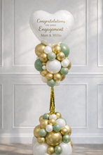 Load image into Gallery viewer, Balloon arrangement with a heart-shaped balloon reading 'Congratulations on your Engagement' against a white paneled wall.
